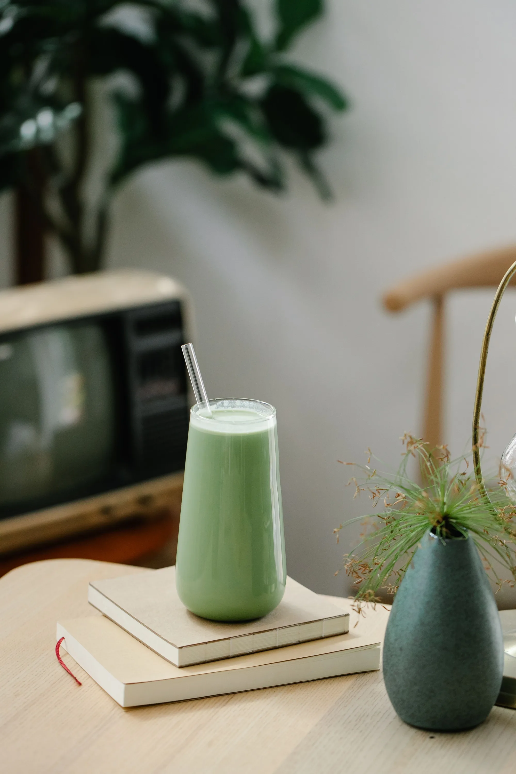 A matcha latte on a table, beside books